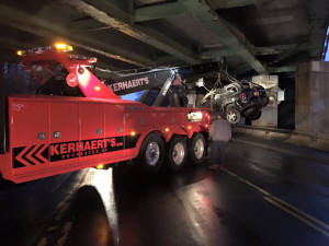 Picture of Kerhaerts 50 ton wrecker bringing SUV over a concrete barrier after it rolled over.